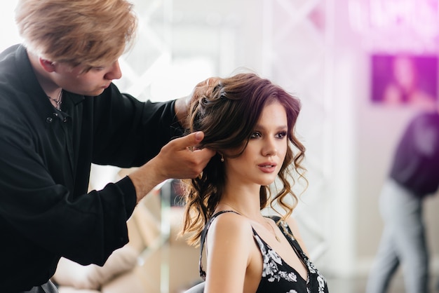 Dans un beau salon de beauté moderne, une styliste professionnelle fait une coupe de cheveux et une coiffure pour une jeune fille. Beauté et mode.