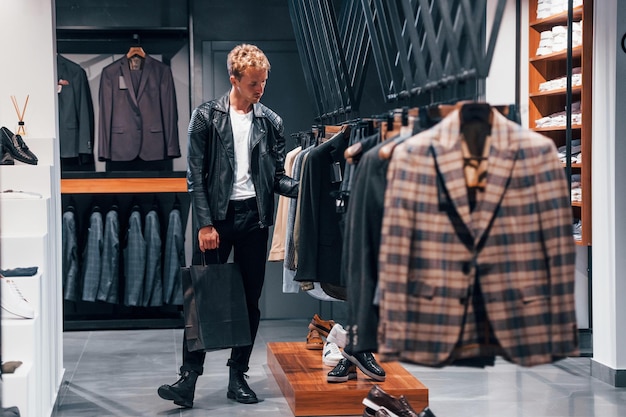 Dans une belle veste noire Jeune homme dans un magasin moderne avec de nouveaux vêtements Vêtements élégants et chers pour hommes