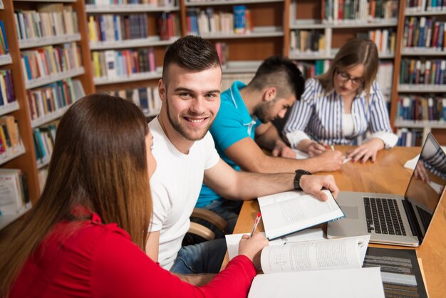 Dans la bibliothèque beau groupe d'étudiants avec ordinateur portable et livres travaillant dans une bibliothèque universitaire de lycée faible profondeur de champ