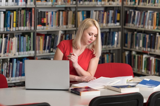 Dans la bibliothèque jolie étudiante avec des livres travaillant dans une bibliothèque universitaire de lycée faible profondeur de champ