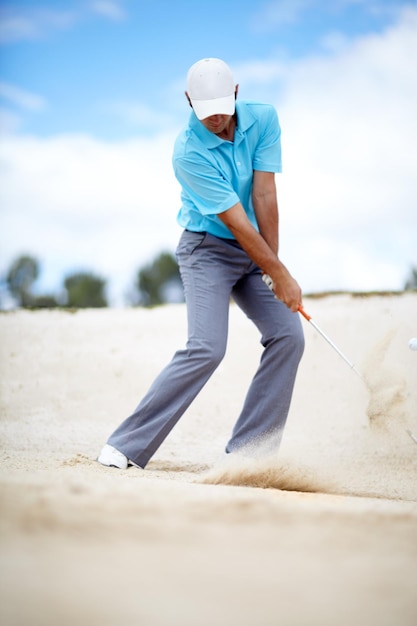 Dans le bunker Une image d'un jeune golfeur sortant sa balle d'un bunker lors d'une partie de golf