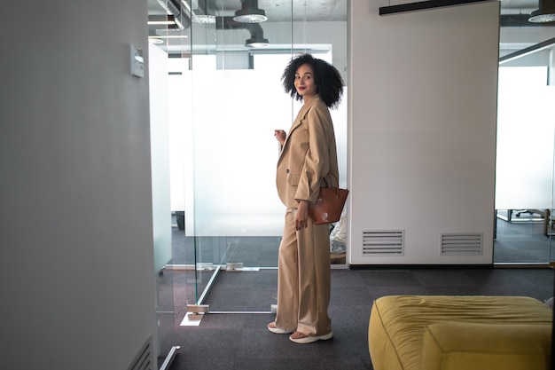 Dans le bureau. Femme d'affaires confiante et déterminée entrant dans un bureau moderne avec des portes vitrées