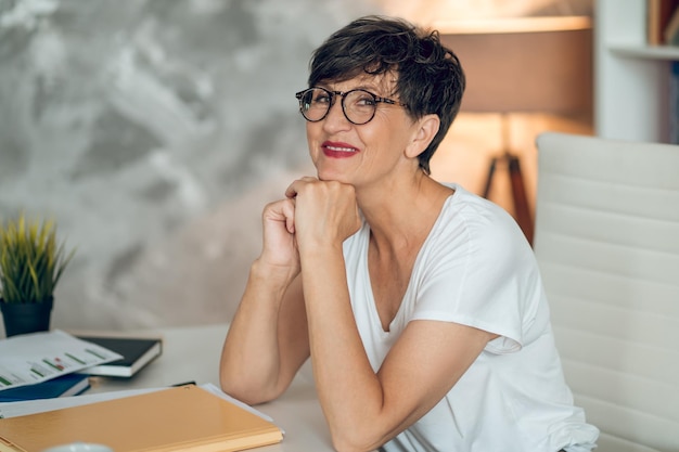 Dans le bureau. Femme brune à lunettes assise à la table du bureau