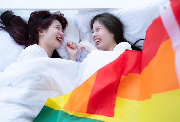 Dans une chambre d'hôtel, un couple LGBT se blottit heureux sur le lit.