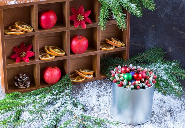 dans un coffret en bois un décor hivernal festif: pommes, tranches d&#39;orange, cornets et décor