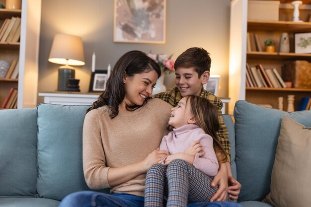 Dans le confort familier de leur salon, une mère, sa fille et son fils se rassemblent sur le canapé. Ils créent une scène d'amour et de connexion. Ils partagent des rires et des histoires de leur vie familiale.