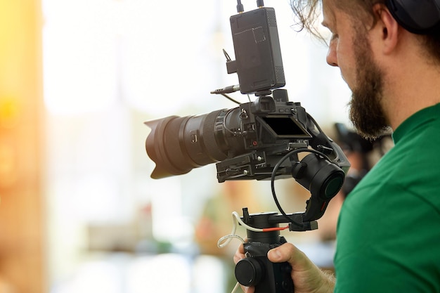 Dans les coulisses du tournage de films ou de produits vidéo L'opérateur avec la caméra sur le plateau sélectionne le plan de prise de vue