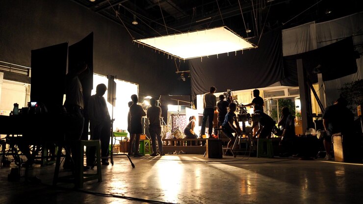 Photo dans les coulisses ou la réalisation d'une équipe de production vidéo et de film travaillant en silhouette de caméra et d'équipement en studio