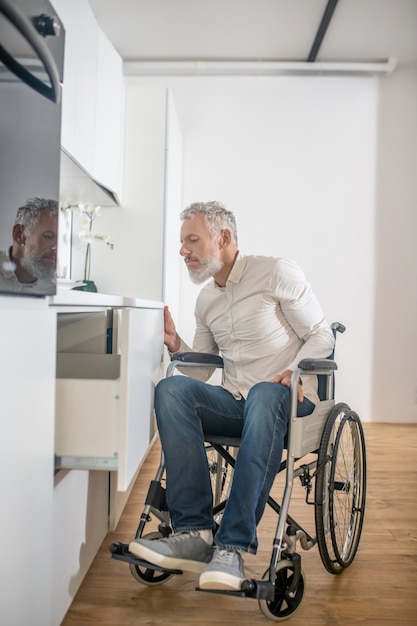 Dans la cuisine. Homme handicapé aux cheveux gris dans la cuisine préparant le petit-déjeuner