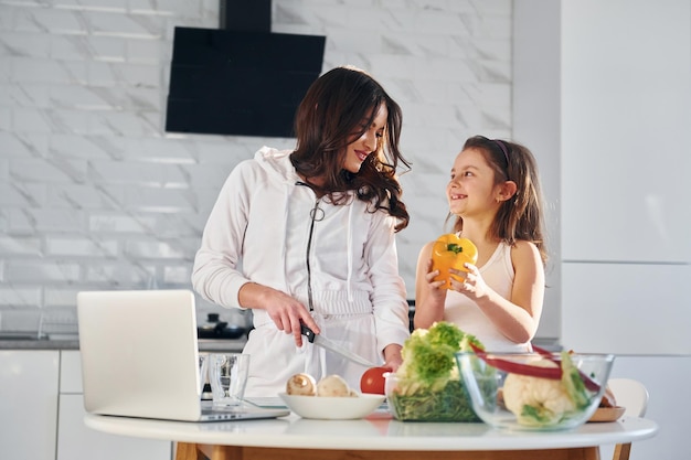 Dans la cuisine, une jeune mère caucasienne avec sa fille est à la maison ensemble