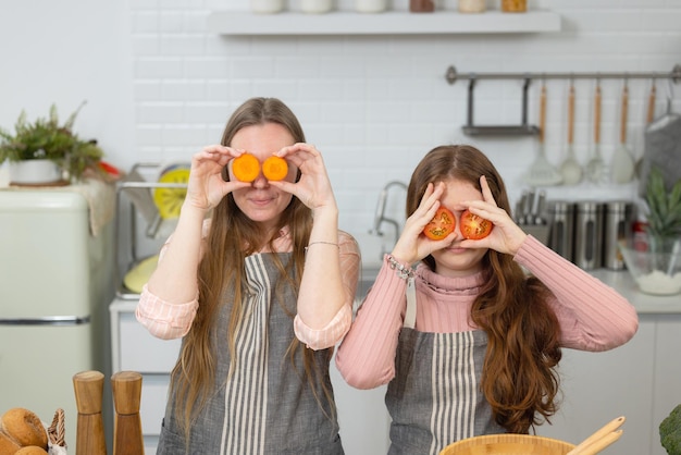 Dans une cuisine moderne et impeccable, une mère et sa fille souriantes montrent comment préparer des légumes à la tomate pour le dîner