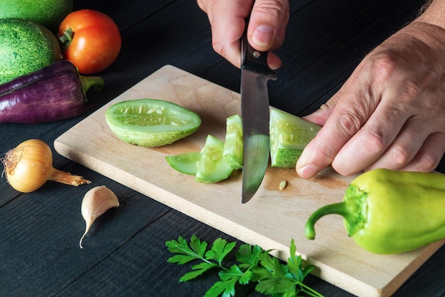 Dans la cuisine d'un restaurant, un chef coupe un concombre mûr pour une salade