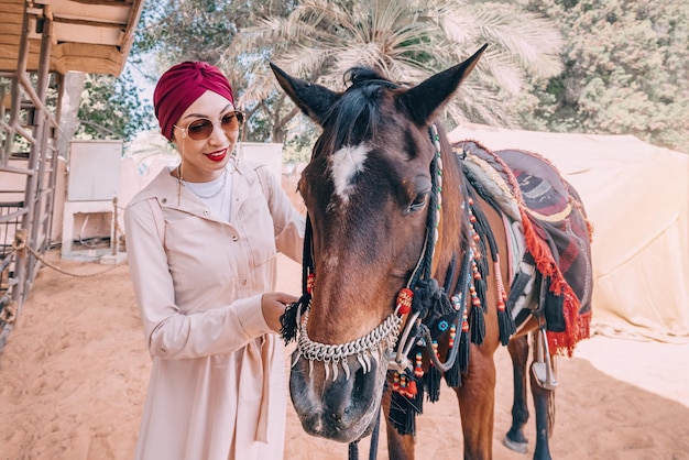 Dans le désert poussiéreux une fille avec une robe flottante mène doucement son cheval arabe leur lien inébranlable et leur voyage sans fin