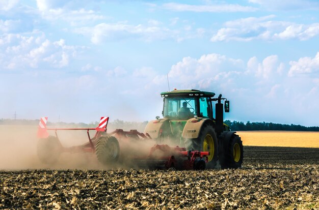 Dans le domaine, la récolte du tracteur. Le fermier essaie de finir le coucher du soleil avec son tracteur.