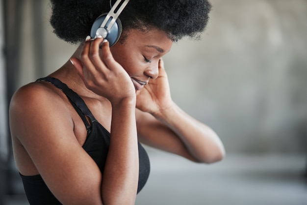 Dans les écouteurs. Portrait de jeune fille afro-américaine dans des vêtements de fitness ayant une pause après l'entraînement