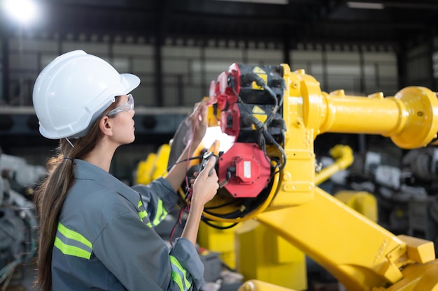 Dans l'entrepôt de robots, une ingénieure inspecte le système électrique de chaque bras robotique avant de le livrer au client.