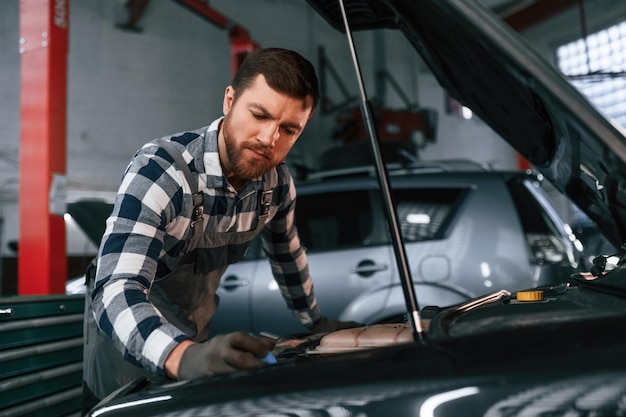 Dans les gants Réparation de voiture L'homme en uniforme travaille dans le salon de l'automobile