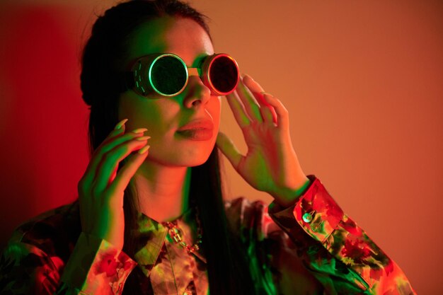 Dans des lunettes de pilote rétro Mode jeune femme debout dans le studio avec néon