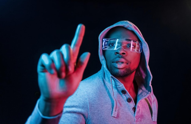 Dans des lunettes spéciales Éclairage néon futuriste Jeune homme afro-américain dans le studio