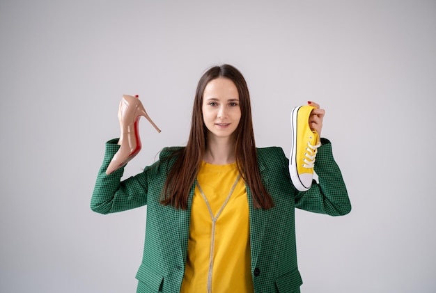 Dans une main des baskets dans l'autre les chaussures d'une jeune fille équilibre vie professionnelle