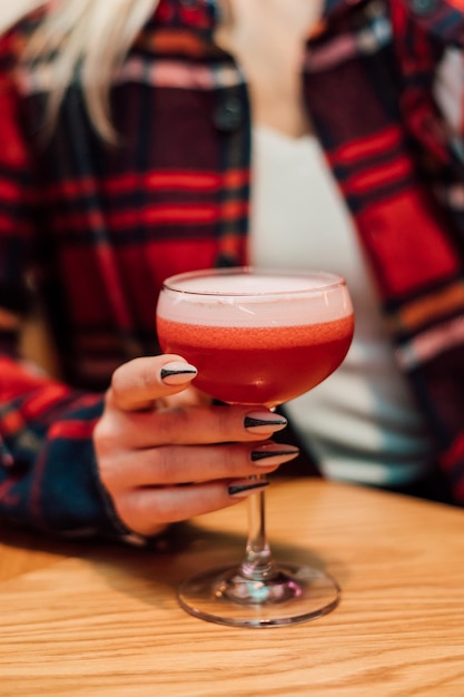 Dans la main d'une jeune femme un verre avec une boisson rouge