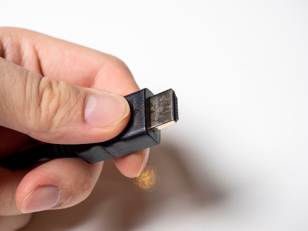 Dans la main masculine se trouve un câble HDMI noir. Câble pour connecter des appareils