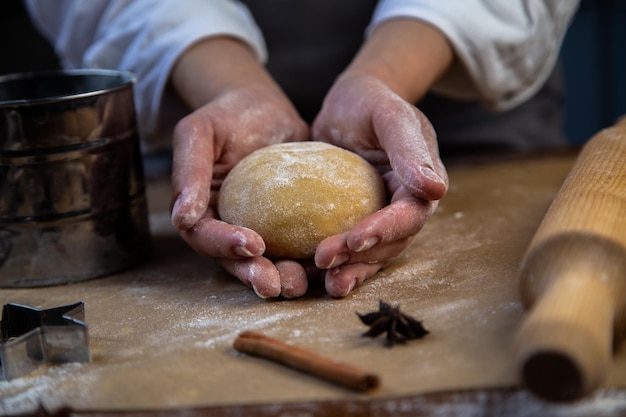 Dans les mains d'un chef pâtissier un rond de pâte tout en farine un rouleau à pâtisserie un moule avec de la farine cl...