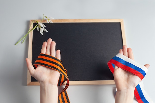 Photo dans les mains des enfants ruban stgeorge et ruban tricolore de russieil y a une place pour l'inscription