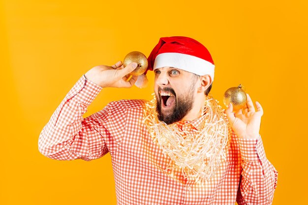 Dans les mains d'un homme qui porte une chemise rouge tient des boules d'or sur un arbre de Noël devant lui