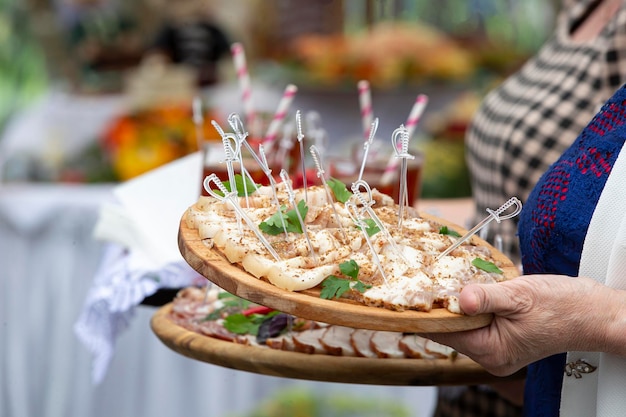 Dans les mains d'un plateau avec des snacks à base de viande pour une table de buffet ou une dégustation