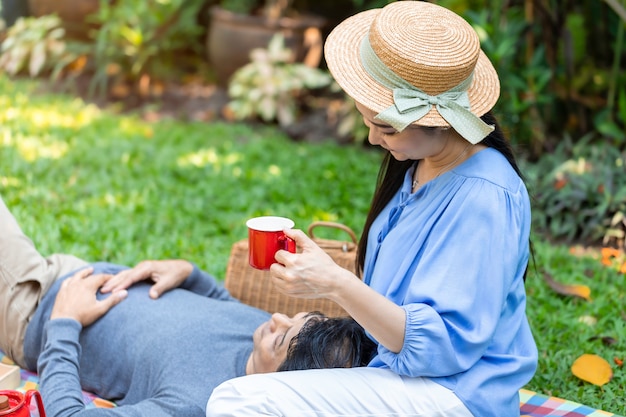 Photo dans la matinée couple asiatique senior buvant café et pique-nique au parc