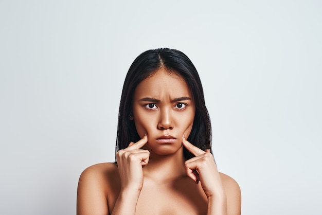 Dans une mauvaise humeur bouleversée jeune femme asiatique faisant une grimace et se sentant triste tout en