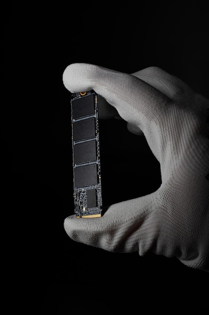 Dans l'obscurité, la main saisit en toute sécurité le disque SSD HighSpeed M2 pour PC