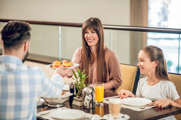 Dans le restaurant. Homme donnant une assiette avec de la nourriture à sa femme souriante