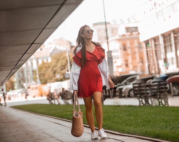 Dans la rue. Une femme élégante dans une robe rouge marchant dans la rue