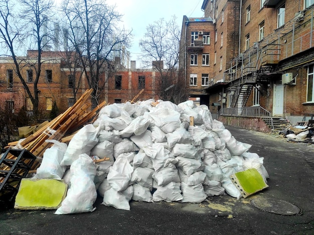 dans la rue se trouve une montagne de sacs blancs de débris de construction après réparations. Beaucoup de déchets.
