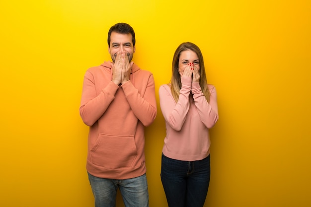 Dans la Saint Valentin Groupe de deux personnes sur fond jaune souriant beaucoup en se couvrant la bouche