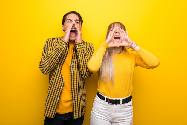 Dans la Saint Valentin Jeune couple sur fond jaune vibrant criant et annonçant quelque chose