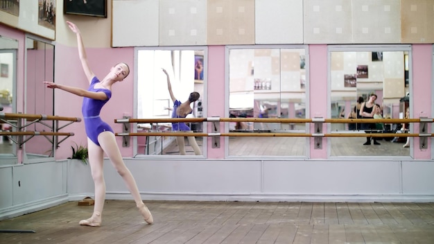 Photo dans la salle de danse, une jeune ballerine en maillot violet effectue un tour chenne sur des chaussures à pointe