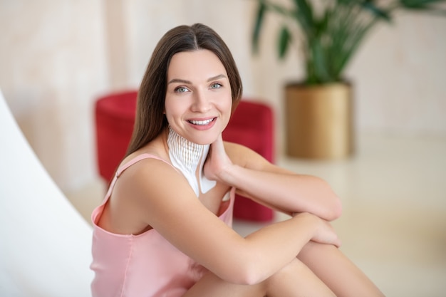 Dans le salon de spa. Jeune femme en lingerie rose et bandes sur son cou à la détente