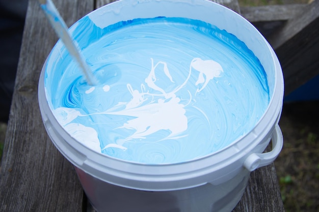 Dans un seau mélanger la peinture bleue et blanche avec un bâton