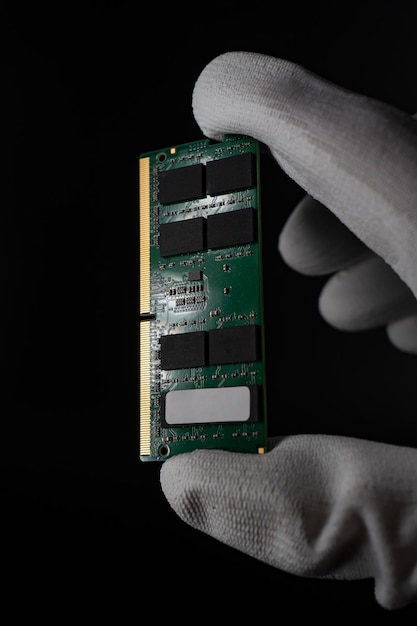 Dans les ténèbres, la main saisit en toute sécurité la RAM DDR4 Sodimm pour PC