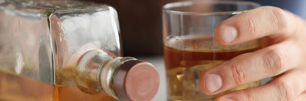 Photo dans le verre à main de l'homme avec de l'alcool à côté du concept de dépendance à l'alcool en bouteille