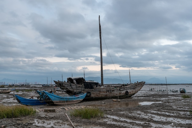 Dans la zone peu profonde avant le lever du soleil le matin, il y a des nuages nuageux et de nombreux bateaux de pêche sur la plage