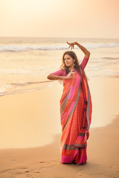 Danse classique indienne Bharatanatyam effectuée par belle femme en vêtements traditionnels au coucher du soleil