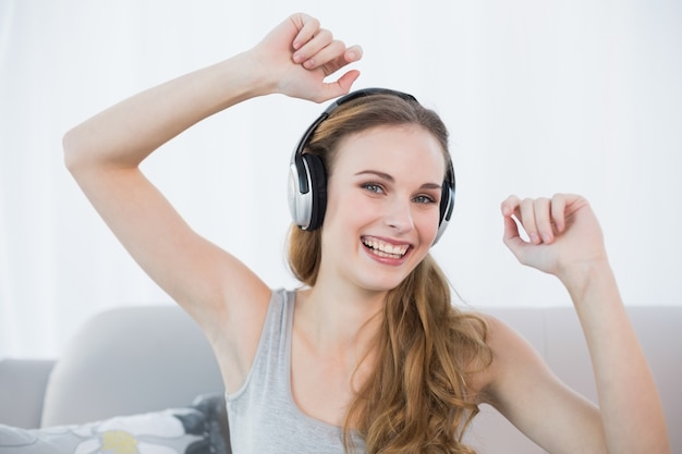 Danse jeune femme assise sur le canapé en écoutant de la musique