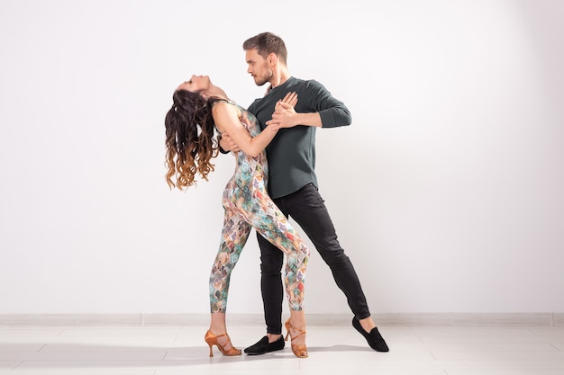 Photo danse sociale, bachata, kizomba, zouk, concept de tango - l'homme embrasse la femme en dansant sur fond blanc avec espace de copie