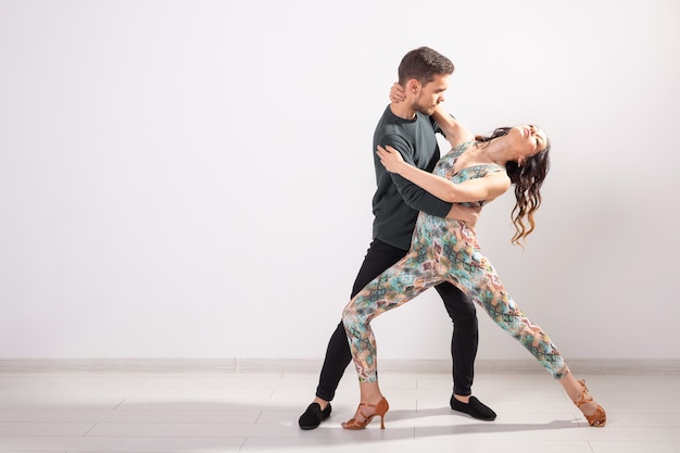 Danse sociale, bachata, salsa, kizomba, zouk, concept de tango - L'homme embrasse la femme en dansant sur fond blanc avec espace de copie