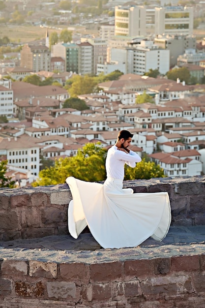 Danse soufie au coucher du soleil. Homme turc exécutant la danse sufi sur le mur du château d'Ankara, Turquie