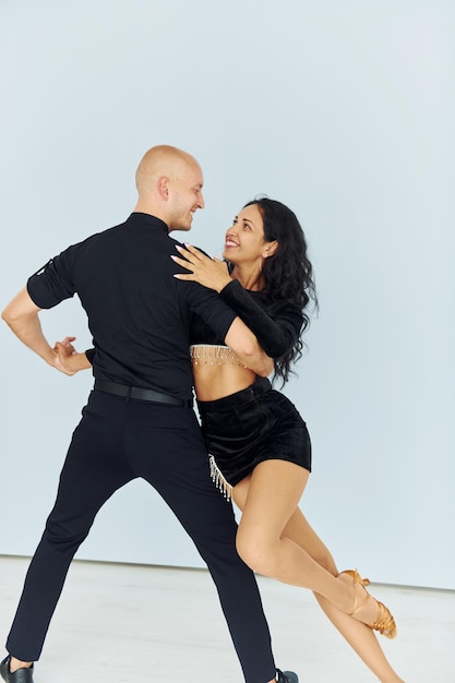 Danse en studio avec fond blanc Un couple joyeux est ensemble à l'intérieur